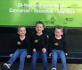 Three boys sitting on a green truck